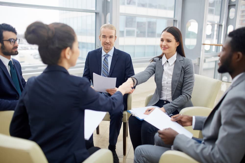 Hiring team welcoming a successful candidate with a handshake in a bright office