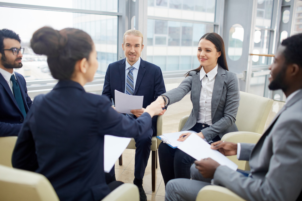 Hiring team welcoming a successful candidate with a handshake in a bright office